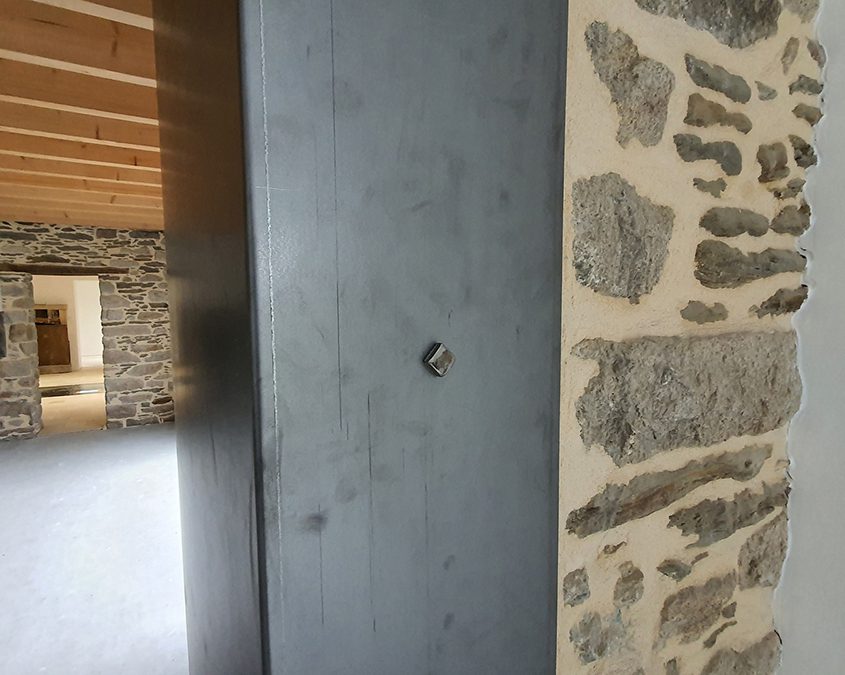 Serrurerie en métal brut avec rivet sur mur en pierre jointoiement à la chaux